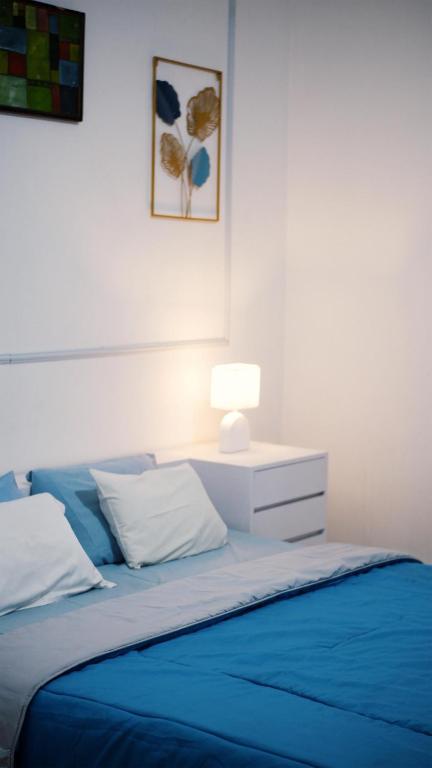 a bed with a blue comforter and a lamp on it at Pondok Kalimaya in Serang