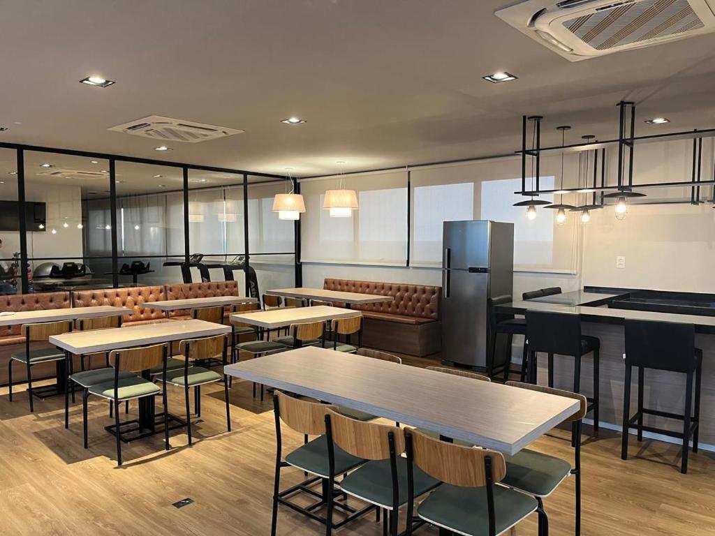 a restaurant with tables and chairs and a refrigerator at Studio Cuiabá in Cuiabá