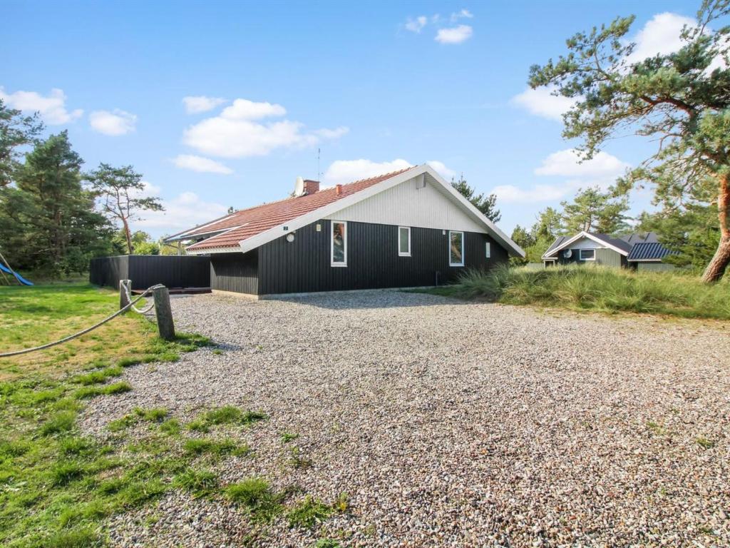 a black and white house with a gravel driveway at Holiday Home Tala - 4km from the sea by Interhome in Blåvand