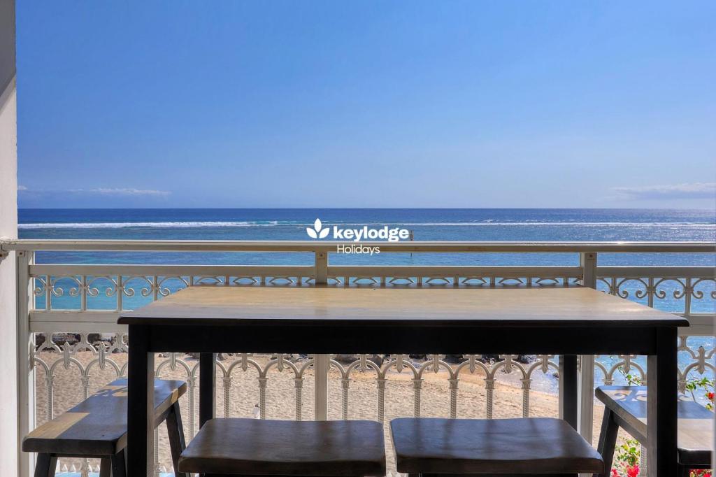 a table and chairs on a balcony overlooking the ocean at Mosala 4 - T3 pieds dans l'eau à Saint-Leu in Saint-Leu