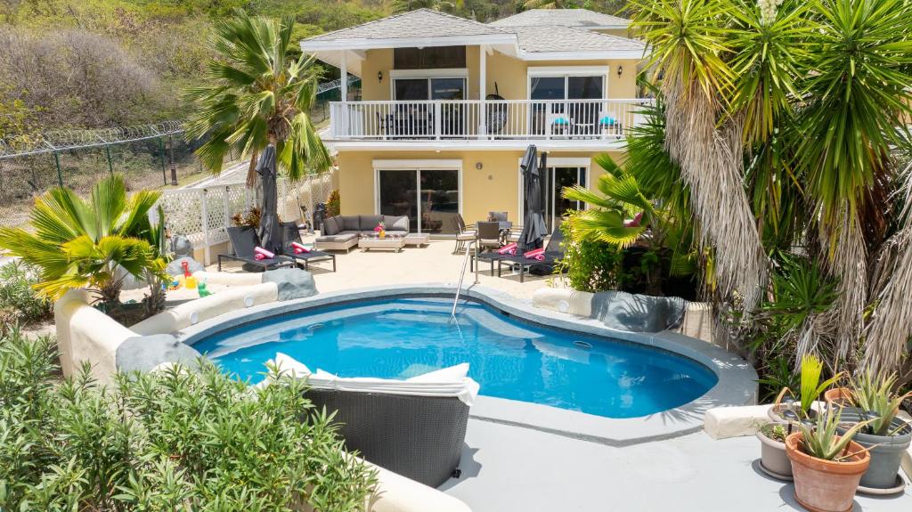 a pool in front of a house with palm trees at Antigua Bay Villa in Bats Cave