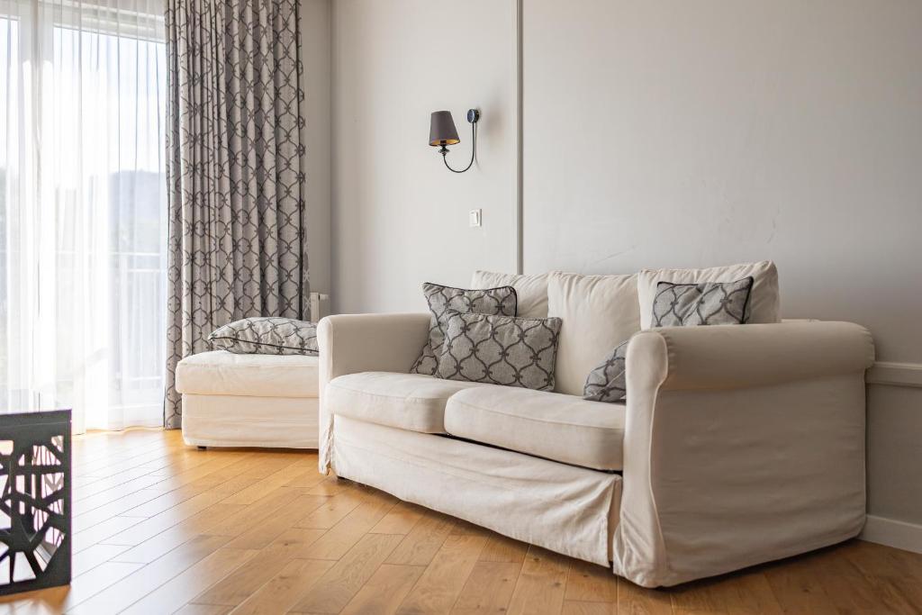a living room with a white couch and a window at Glow Apartments, Apartamenty Zaspa, Dywizjonu 303 in Gdańsk