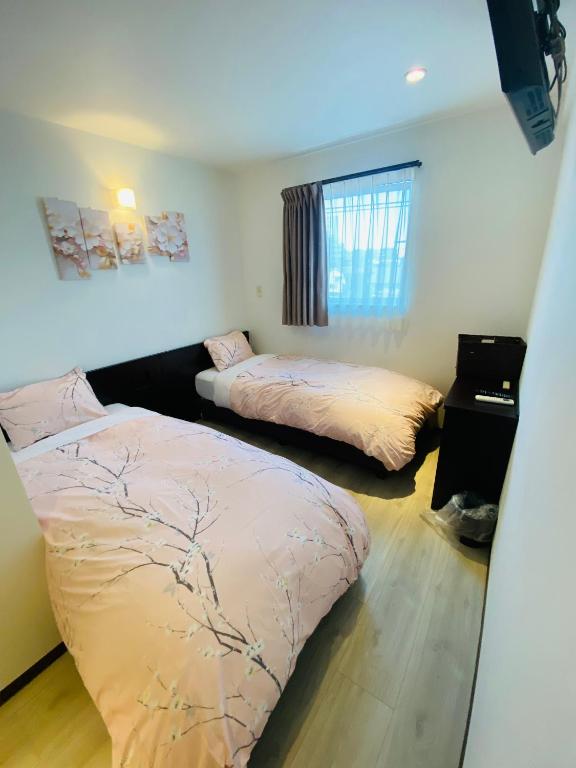 a bedroom with two beds and a window at Omori Happy Smile Hotel-Self Check In in Tokyo