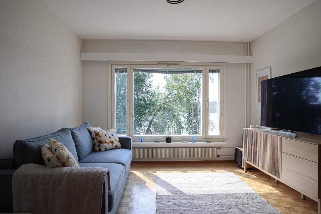a living room with a blue couch and a large window at Arctic Sauna Suite Rovaniemi in Rovaniemi
