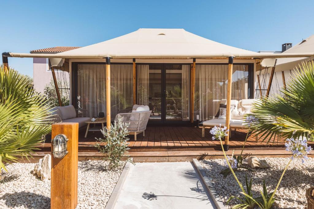 a gazebo with chairs and an umbrella at Glamping Resort Olive and Sea in Bibinje