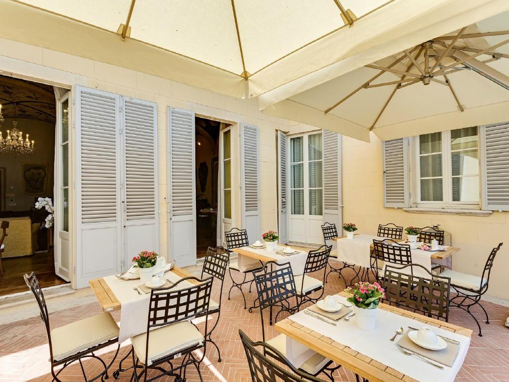 d'une terrasse avec des tables, des chaises et un parasol. dans l'établissement Relais degli Angeli Residenza d'Epoca, à Sienne