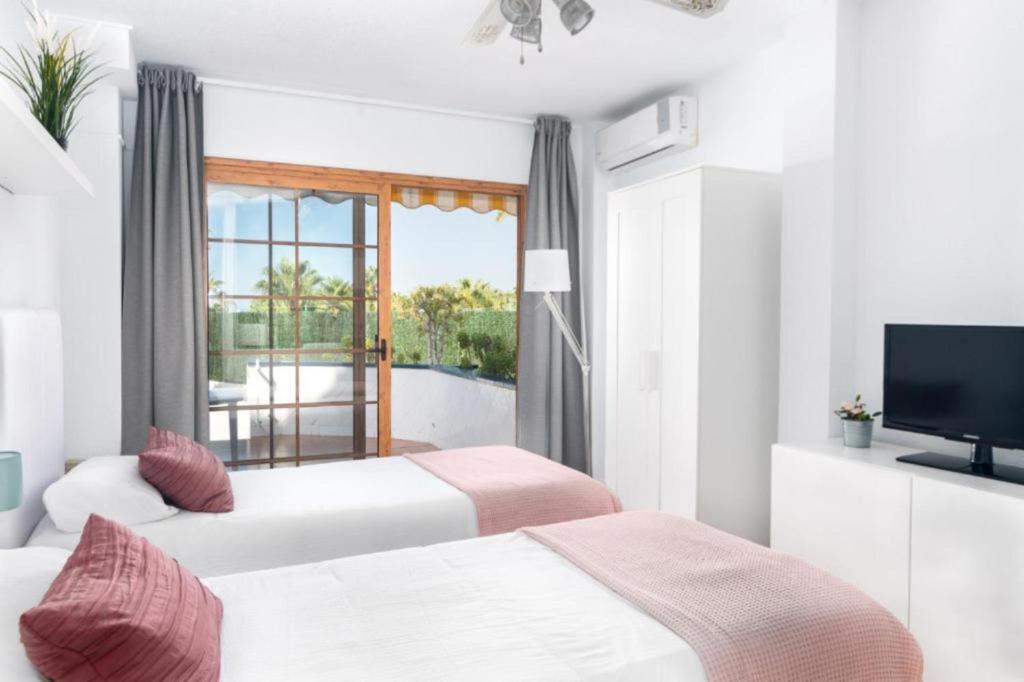 a hotel room with two beds and a television at Moderno estudio con Terraza y Piscina en Costa Adeje in Costa de Adeje