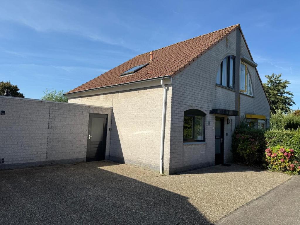 a white brick building with a garage at Vakantiehuis Strand ,water,met infraroodsauna in Breskens