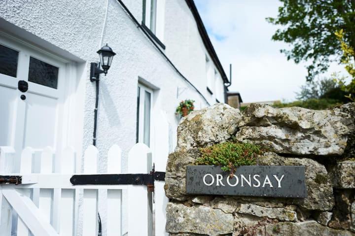 a sign on a stone wall in front of a house at Oronsay in Moffat
