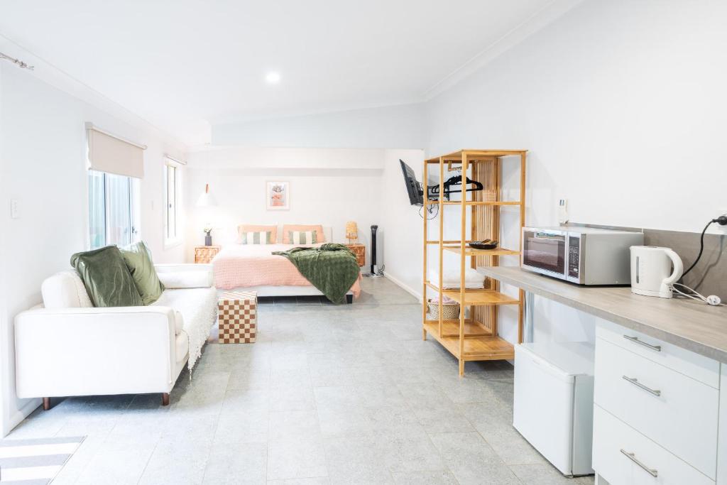 Una sala de estar con una cama y una cocina. en Pink Muse, 3 Mins To Ettalong Beach, en Ettalong Beach