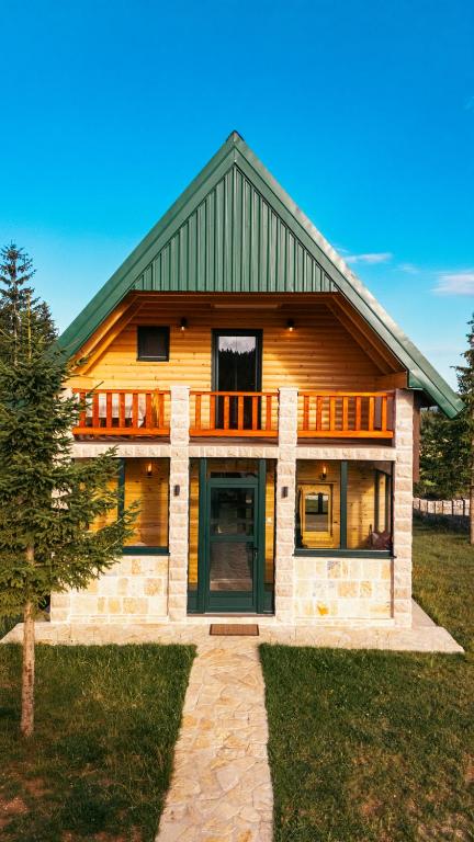 a large wooden house with a green door at Villas Hidden Paradise in Žabljak