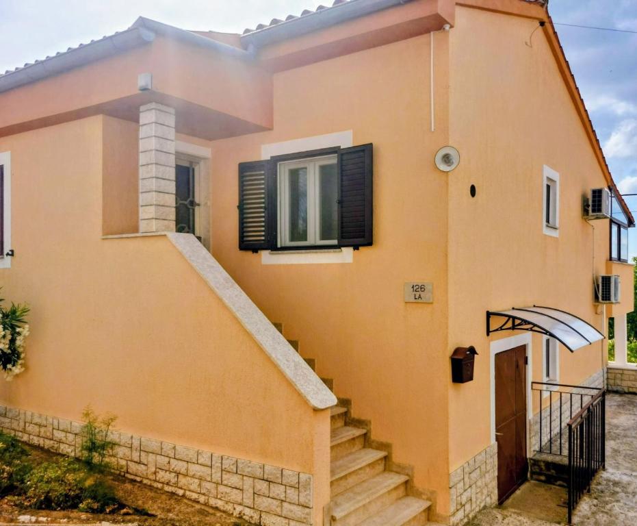 a yellow house with stairs in front of it at Apartment Tina in Karojba