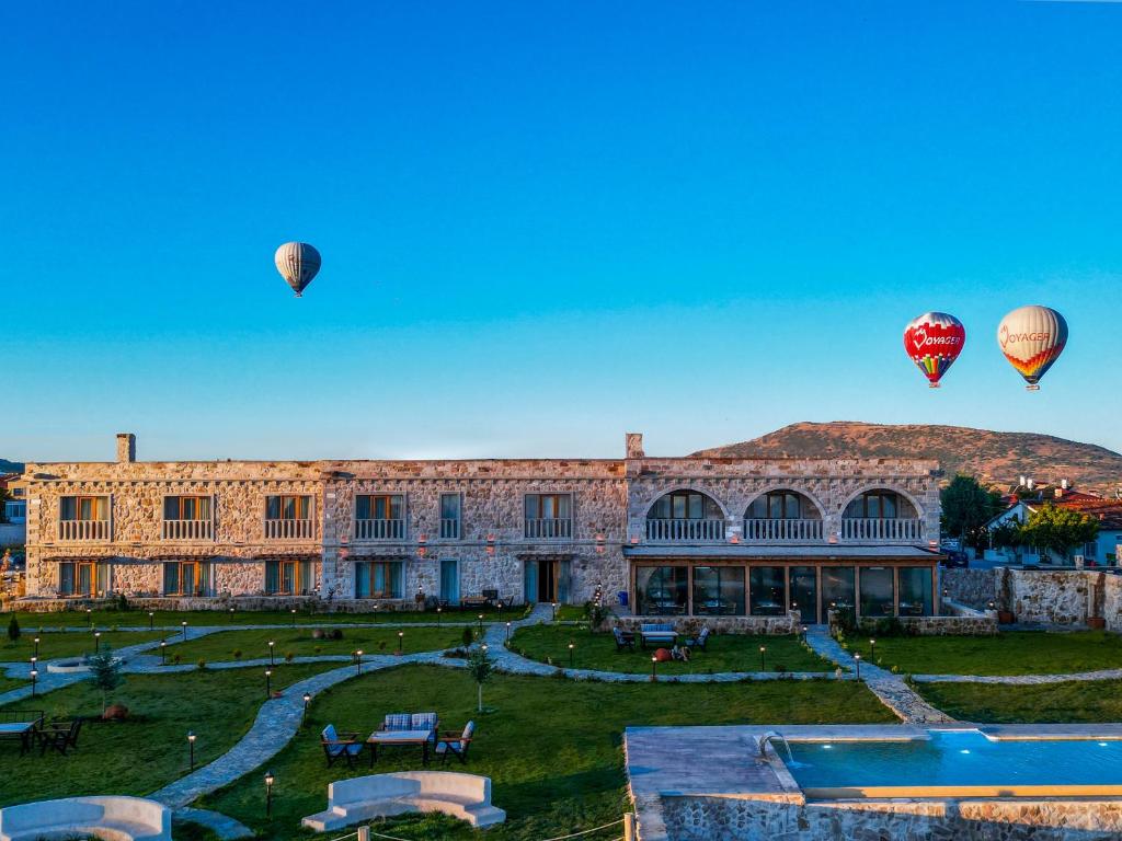 two hot air balloons flying over a building at La Fairy Cappadocia in Uçhisar