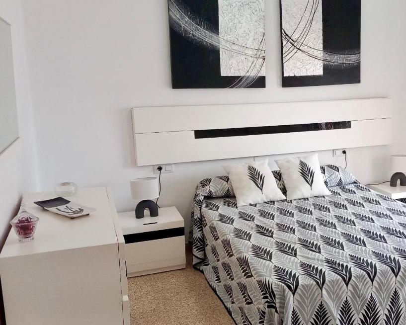 a white bedroom with a bed and a desk at Apartament La Calita in Peniscola