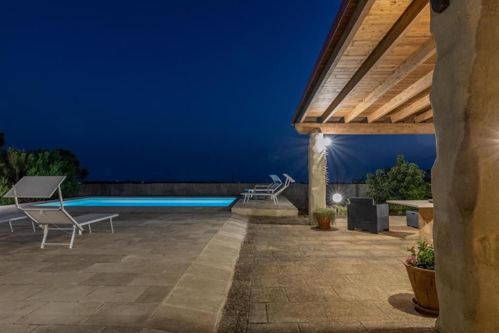 une terrasse avec une piscine la nuit dans l'établissement Trullo la Ficarigna, à Alliste