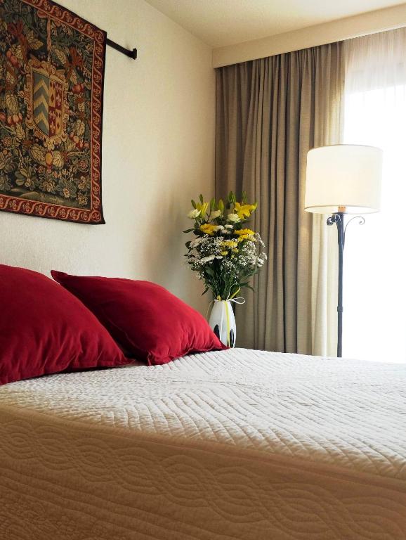 a bedroom with a bed with red pillows and a vase of flowers at STRAVINSKY Apartments Avignon - Get our Last best deals ! in Avignon