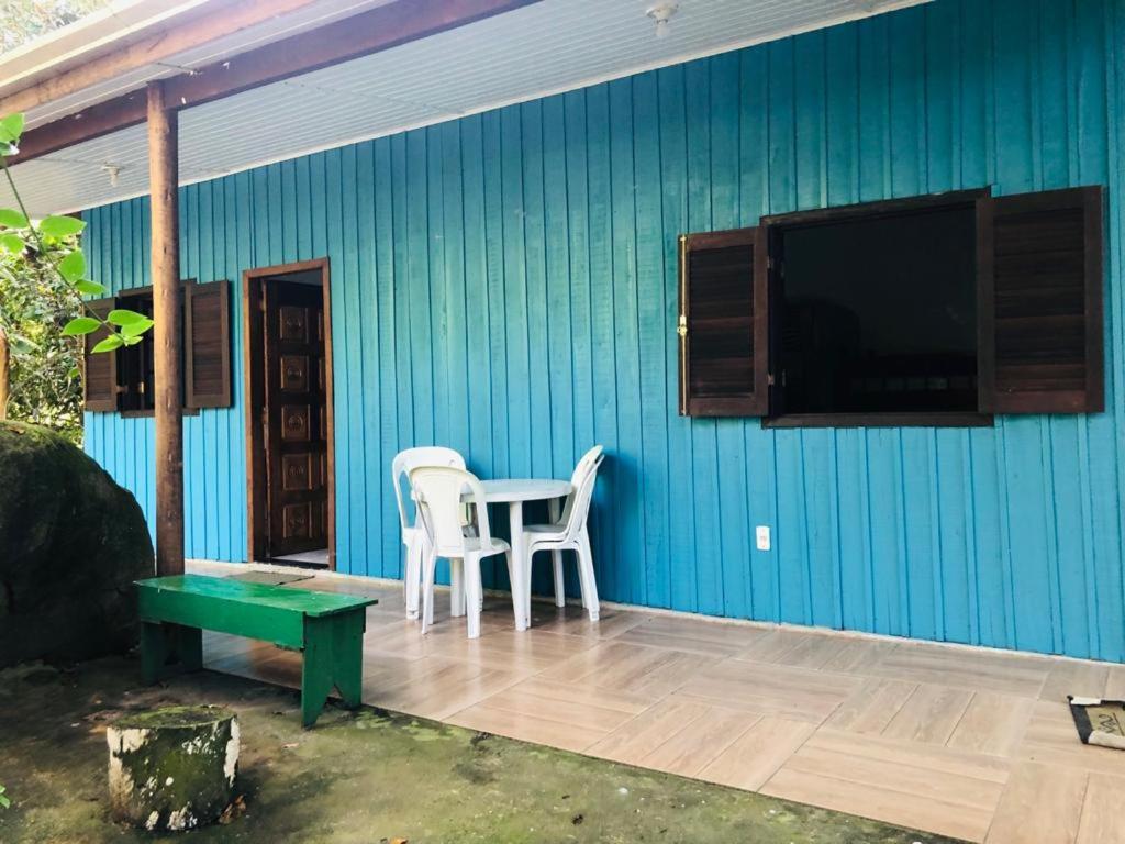 a patio with two chairs and a table and a tv at Chalé Mar e Montanha - Próximo praia do cepilho in Paraty