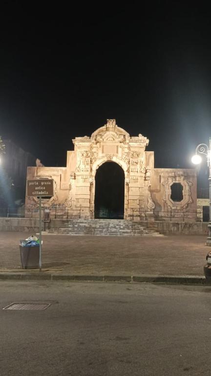 a stone building with an arch at night at La Maison dello Stretto in Messina