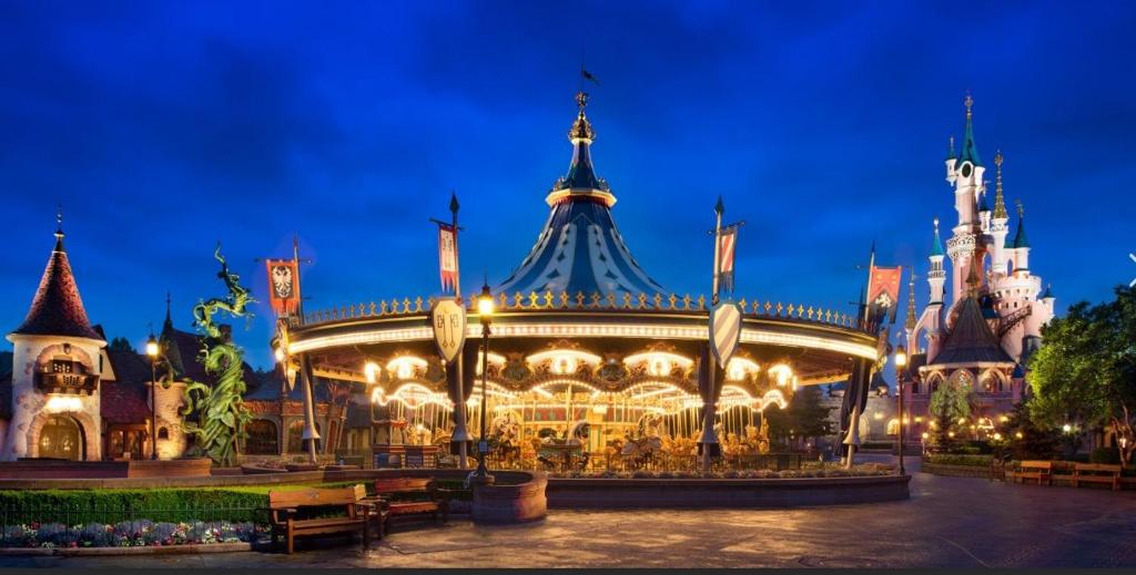 a carousel in front of a castle at night at Appartement spacieux et 5 minutes DISNEY LAND PARIS in Bailly-Romainvilliers