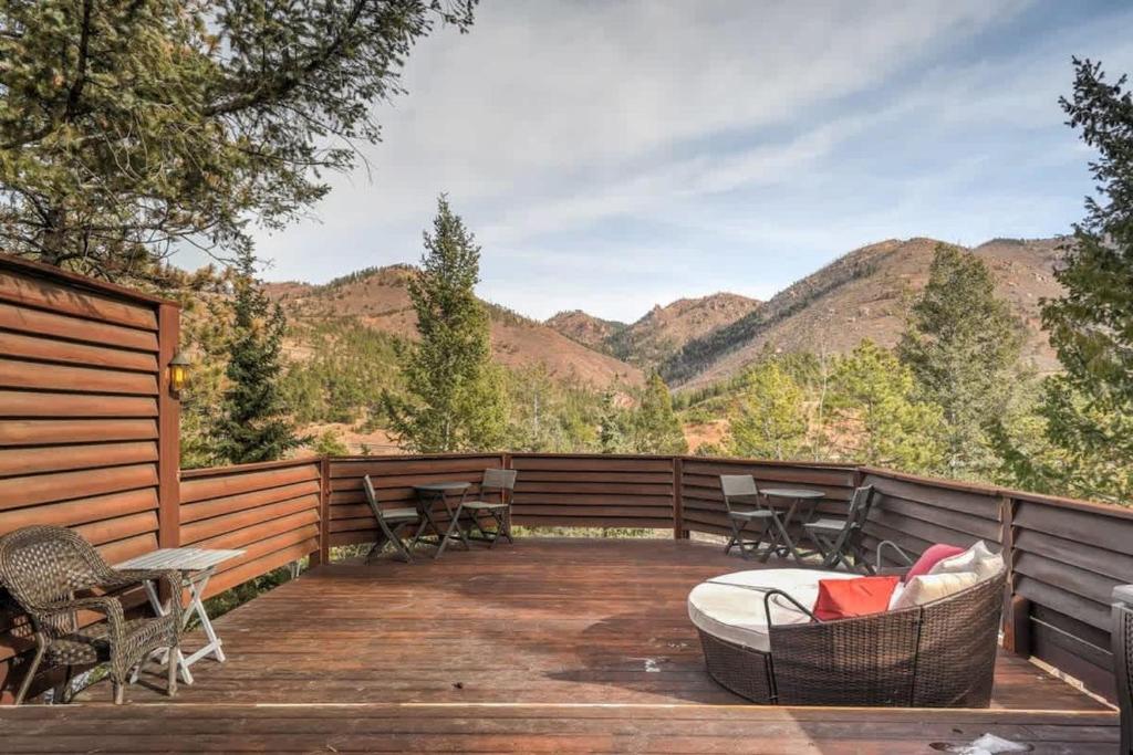 a deck with chairs and a table with mountains in the background at 4 Bdrm Amazing Veiws in Cascade-Chipita Park