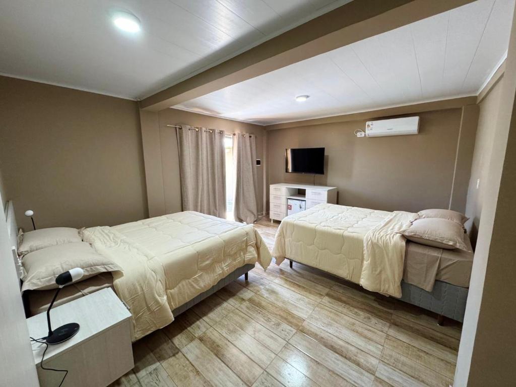 a hotel room with two beds and a television at Hotel SMA in Puerto Iguazú