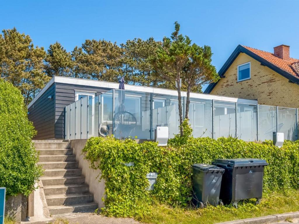 een huis met glazen wanden en trappen en twee vuilnisbakken bij Apartment Sibyll - 2km from the sea by Interhome in Skagen