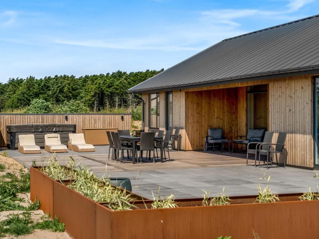 Un patio con mesa y sillas y un edificio. en Holiday Home Merta - 800m from the sea by Interhome, en Løkken