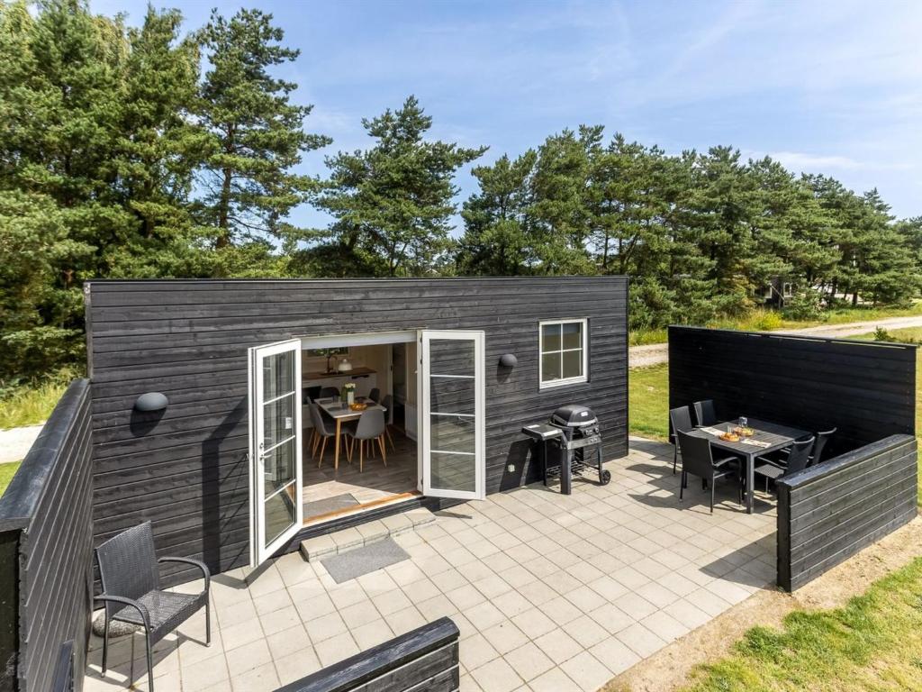 a small black tiny house with a patio at Holiday Home Brun - 900m from the sea by Interhome in Marielyst