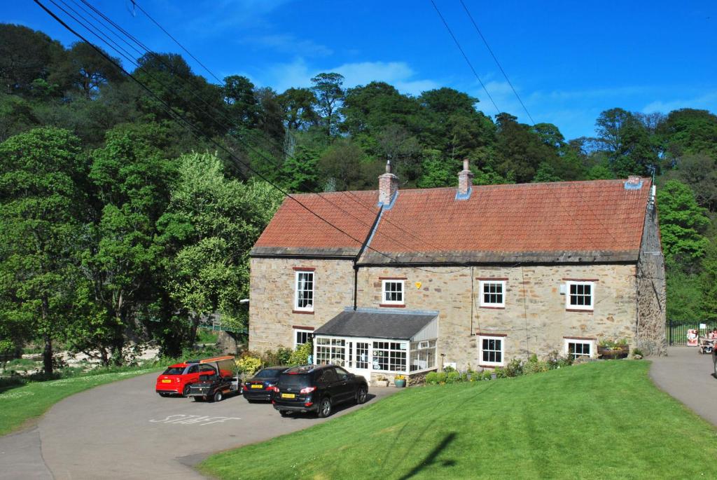 uma casa de pedra com carros estacionados em frente em Apartment Finchale Abbey em Durham