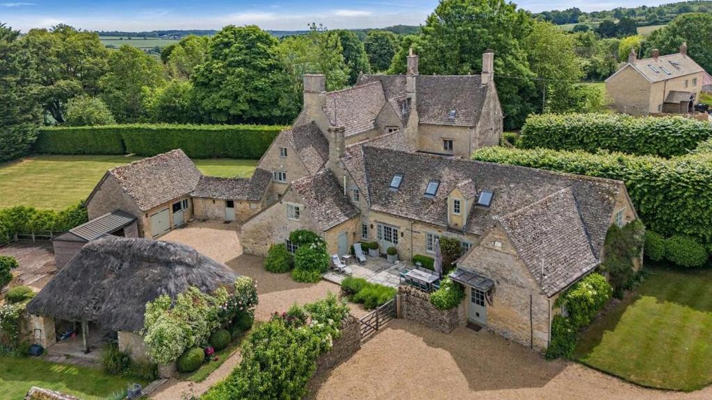 una vista aerea di una grande casa in pietra con alberi di Finstock Manor a Finstock