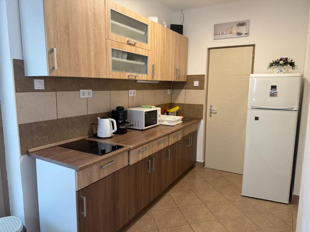 a kitchen with wooden cabinets and a white refrigerator at Mária Vendégház in Bogács