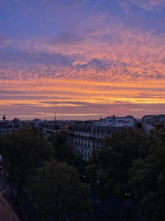 a sunset over a city with trees and buildings at Eiffel Tower View Apartment in Paris