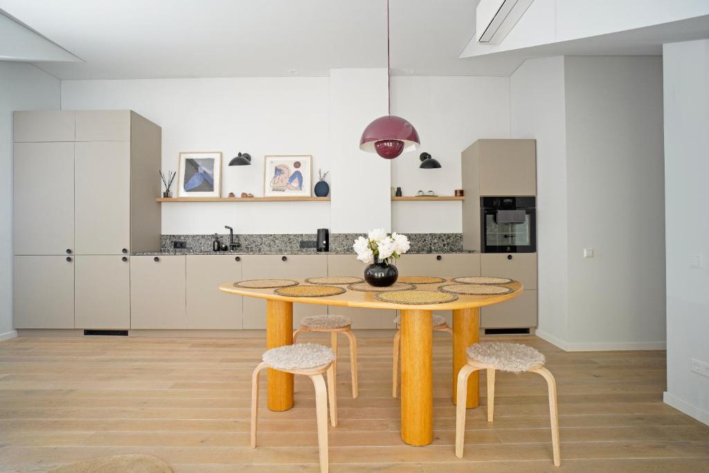 eine Küche mit einem Holztisch und Hockern in der Unterkunft N i d e l ê in Nida