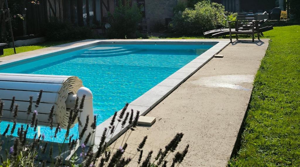 a swimming pool with blue water in a yard at Gite de charme avec piscine in Boissy-la-Rivière