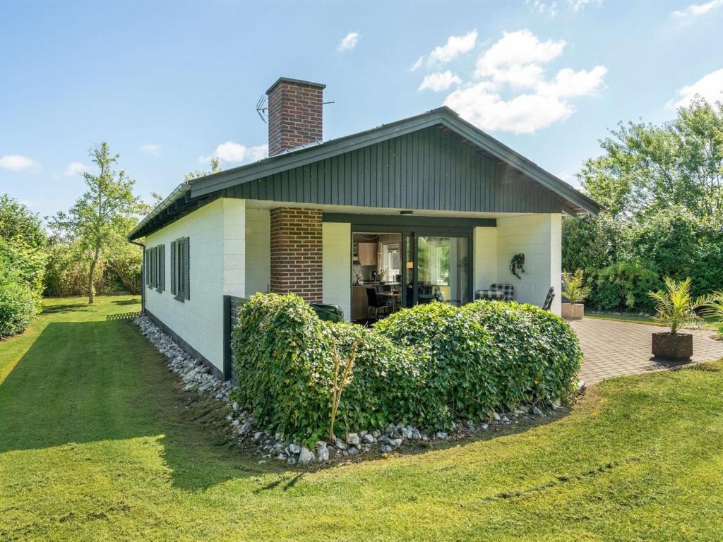 a small white house with bushes in front of it at Holiday Home Suni - 400m from the sea by Interhome in Middelfart