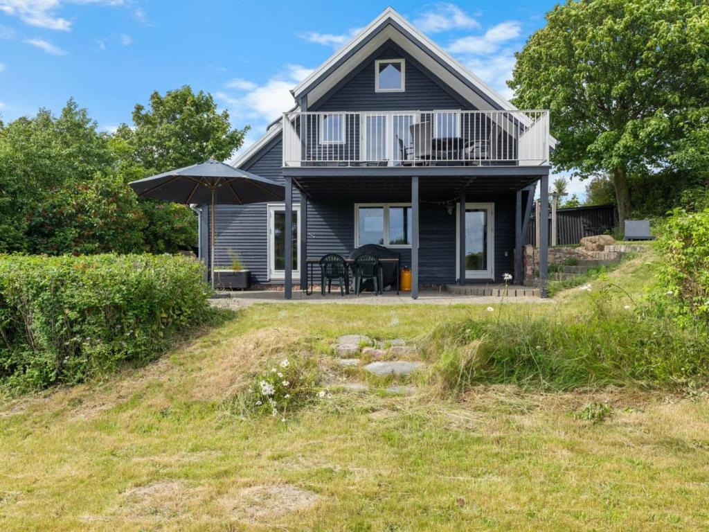 a black house with an umbrella on a yard at Holiday Home Chayton - 450m from the sea by Interhome in Fåborg