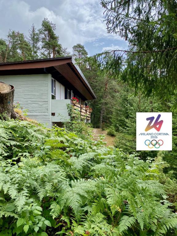 a building with a sign next to a field of plants at Ca'Mugo, a chalet in the magic woods, near Cortina in Vodo Cadore