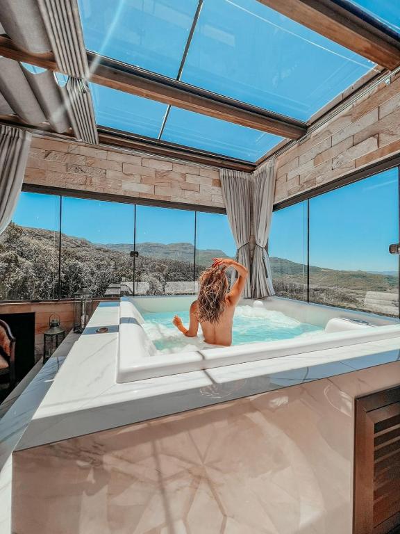 a woman in a hot tub in a room with windows at Discovery Canyon in Praia Grande