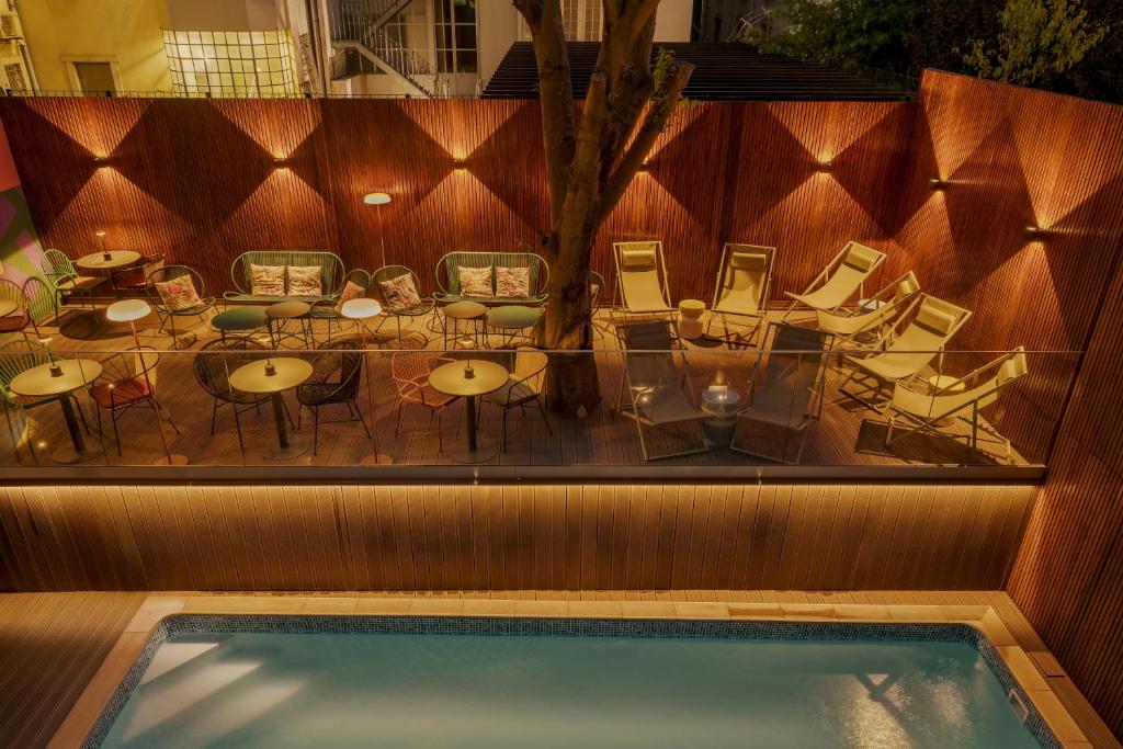 An illuminated courtyard pool is bordered by loungers and café-style seating.