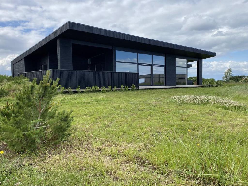 a black house on top of a grass field at Holiday Home Anelle - 500m from the sea by Interhome in Børkop