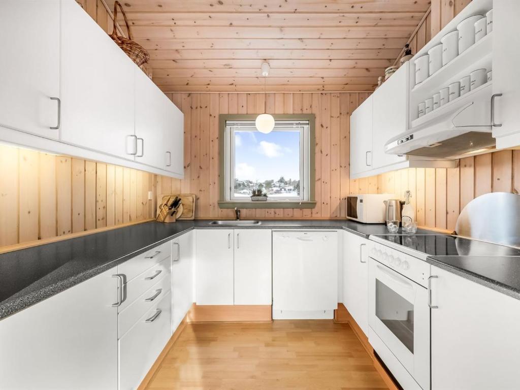 a kitchen with white cabinets and a window at Holiday Home Kai - 500m to the fjord by Interhome in Struer