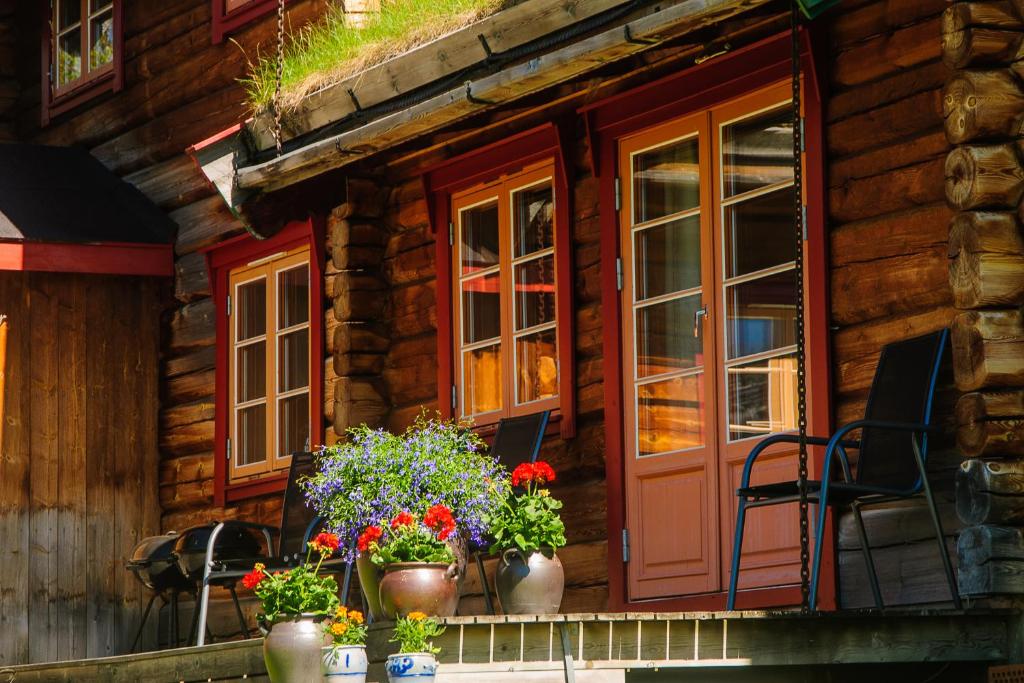 a wooden house with flowers on a balcony at Øvre Nordli Rondane Utleie Sollia Friluftsliv in Sollia