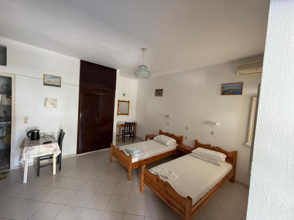 um quarto com duas camas e uma mesa em Helena & Giorgio Rooms Cfu em Agios Georgios