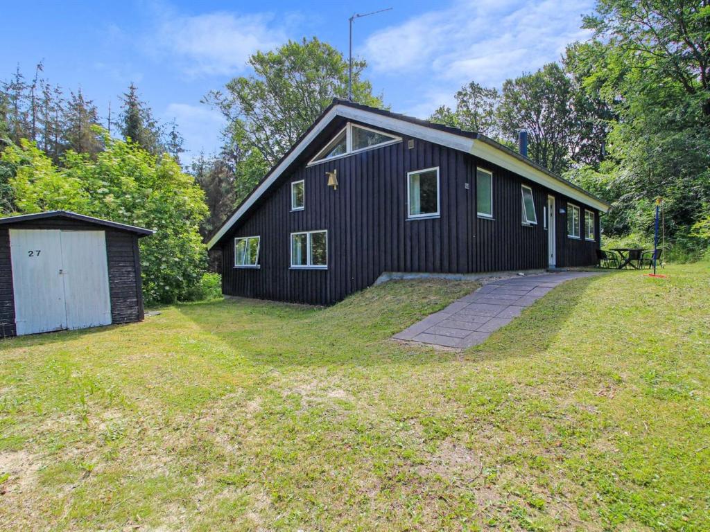 a black house with a garage and a yard at Holiday Home Ernestina - 500m from the sea by Interhome in Glesborg