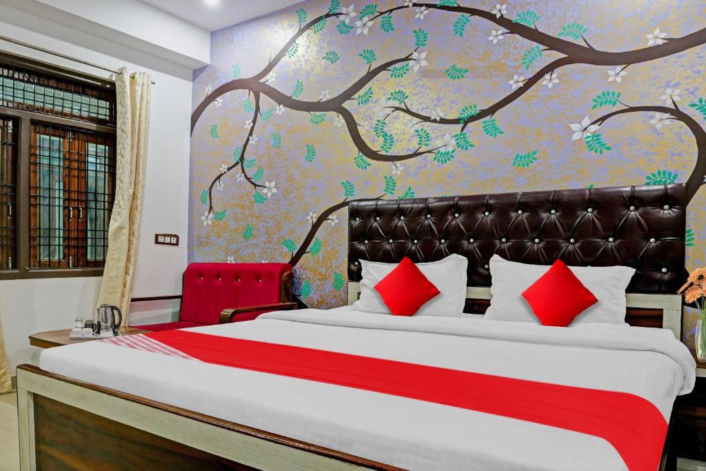 een slaapkamer met een groot bed en een muurschildering van bomen bij Hotel O Atharv Palace in Prayagraj