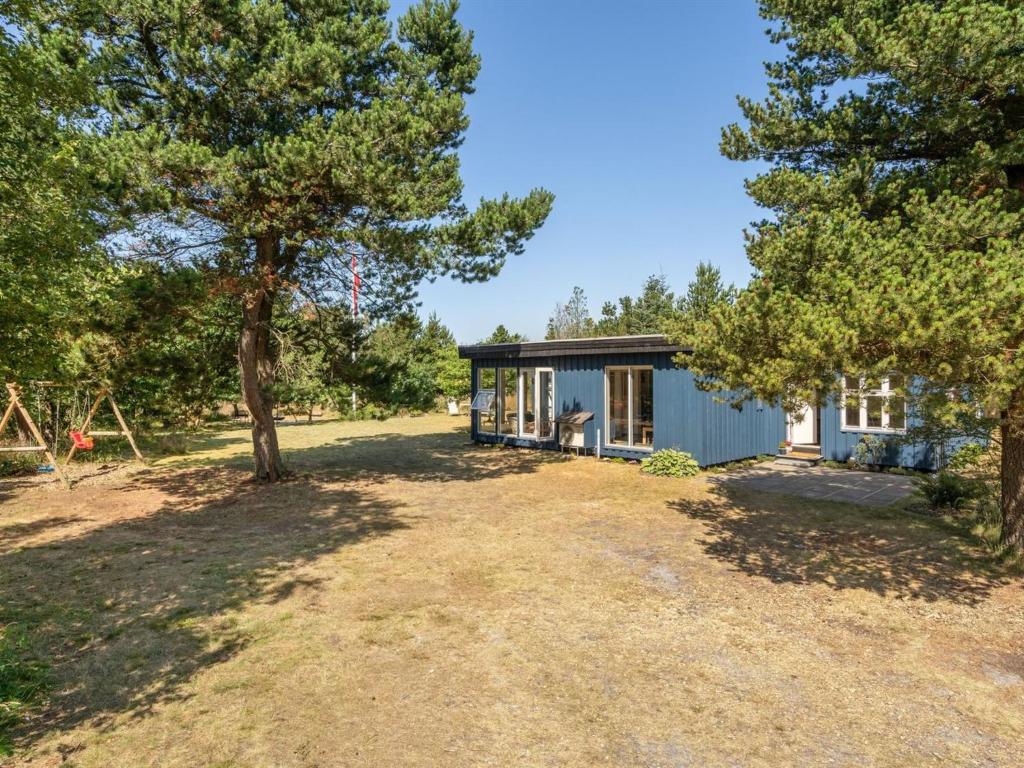 a small blue cottage with trees in the yard at Holiday Home Sebastian - 100m to the fjord by Interhome in Thyholm