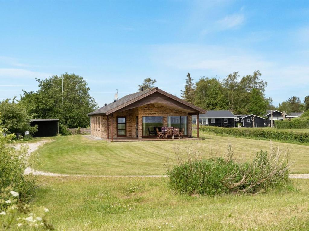 a log cabin in a field with a grass yard at Holiday Home Roope - 50m from the sea by Interhome in Storvorde