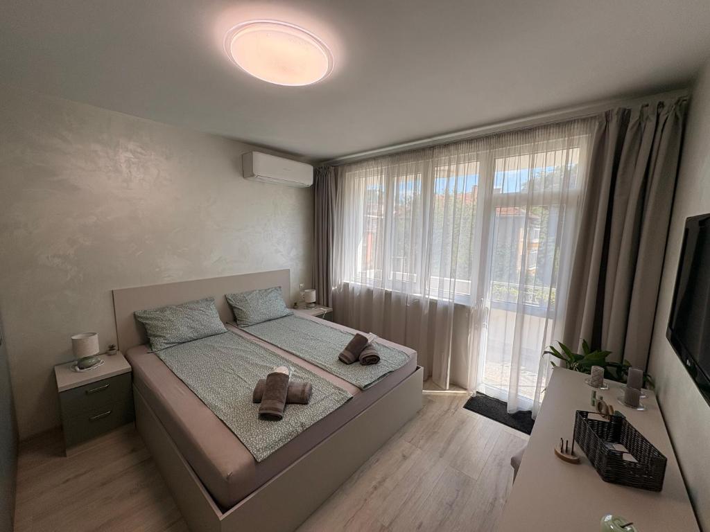 ein Schlafzimmer mit einem Bett und einem großen Fenster in der Unterkunft В къщи in Weliko Tarnowo