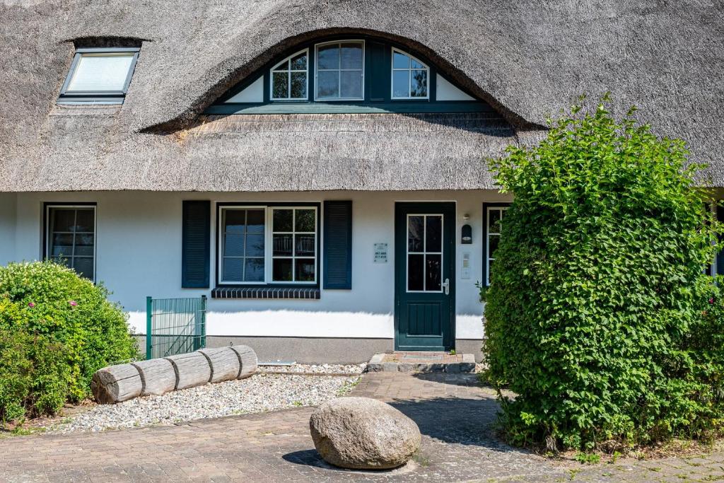 una casa con il tetto di paglia e una porta verde di Dünentraum a Neuhaus