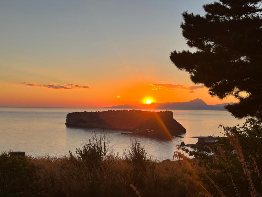 a sunset over the ocean with a rock in the water at STILL HOUSE in San Nicola Arcella